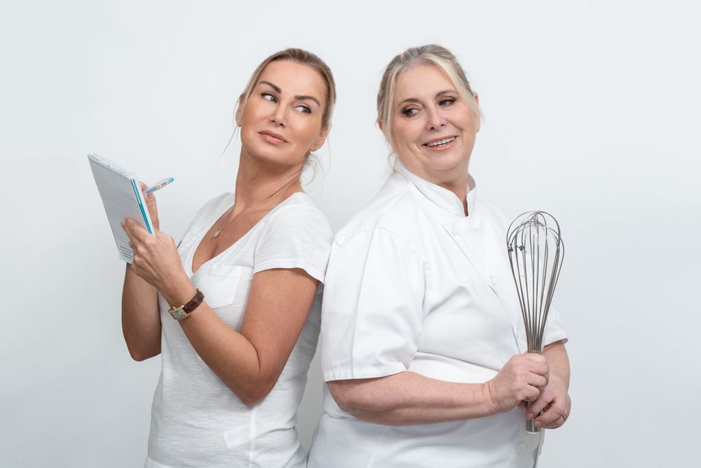 Two women in a studio setting discussing and planning culinary tasks with creative engagement.